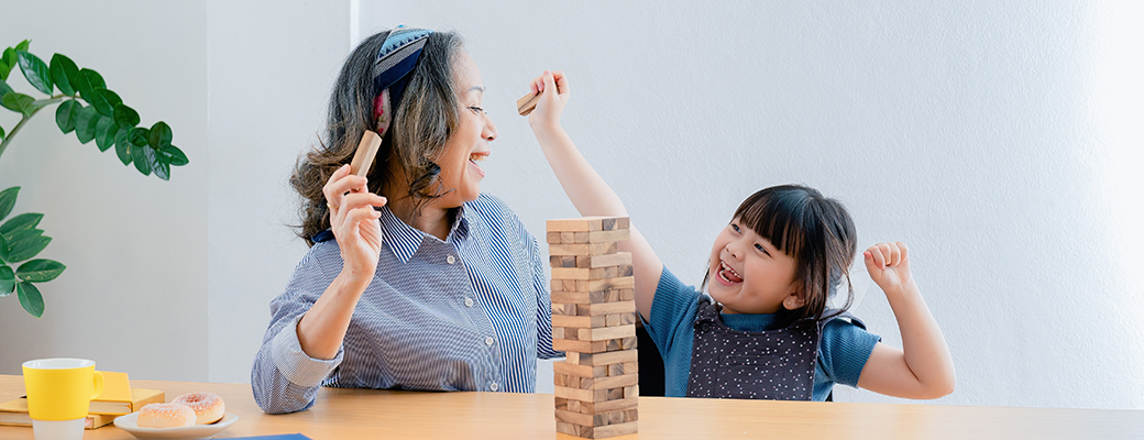 Image of middle-aged woman and young girl playing with stacked Jenga blocks